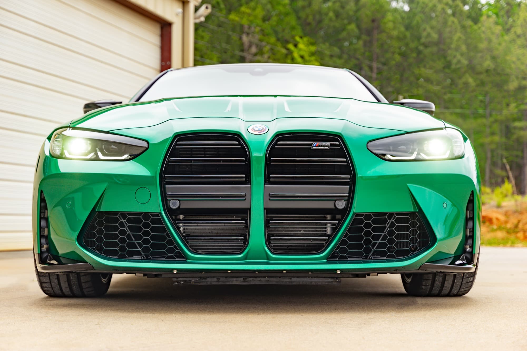 Head-on view of a green BMW M4 showing its large vertical grille, headlights and front bumper