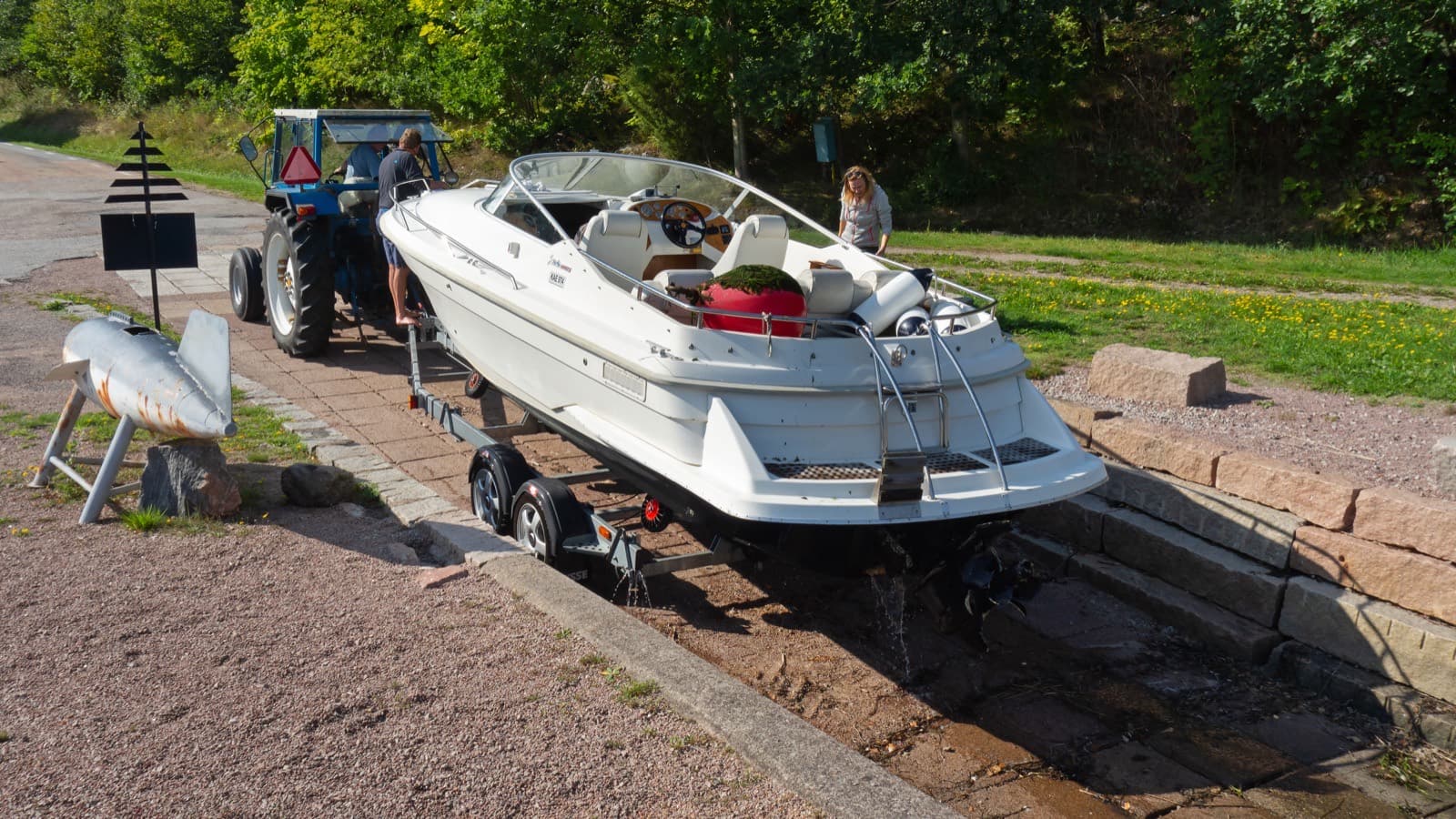 A white cuddy-style runabout on a trailer at the top of a stone boat ramp