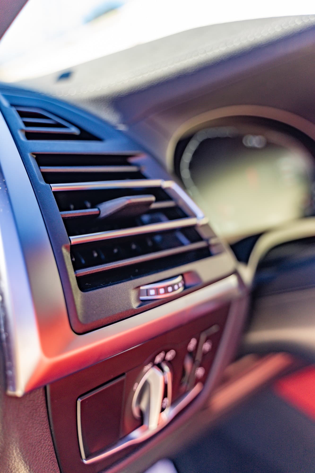 Close-up of a car dashboard air vent and instrument cluster in soft daylight