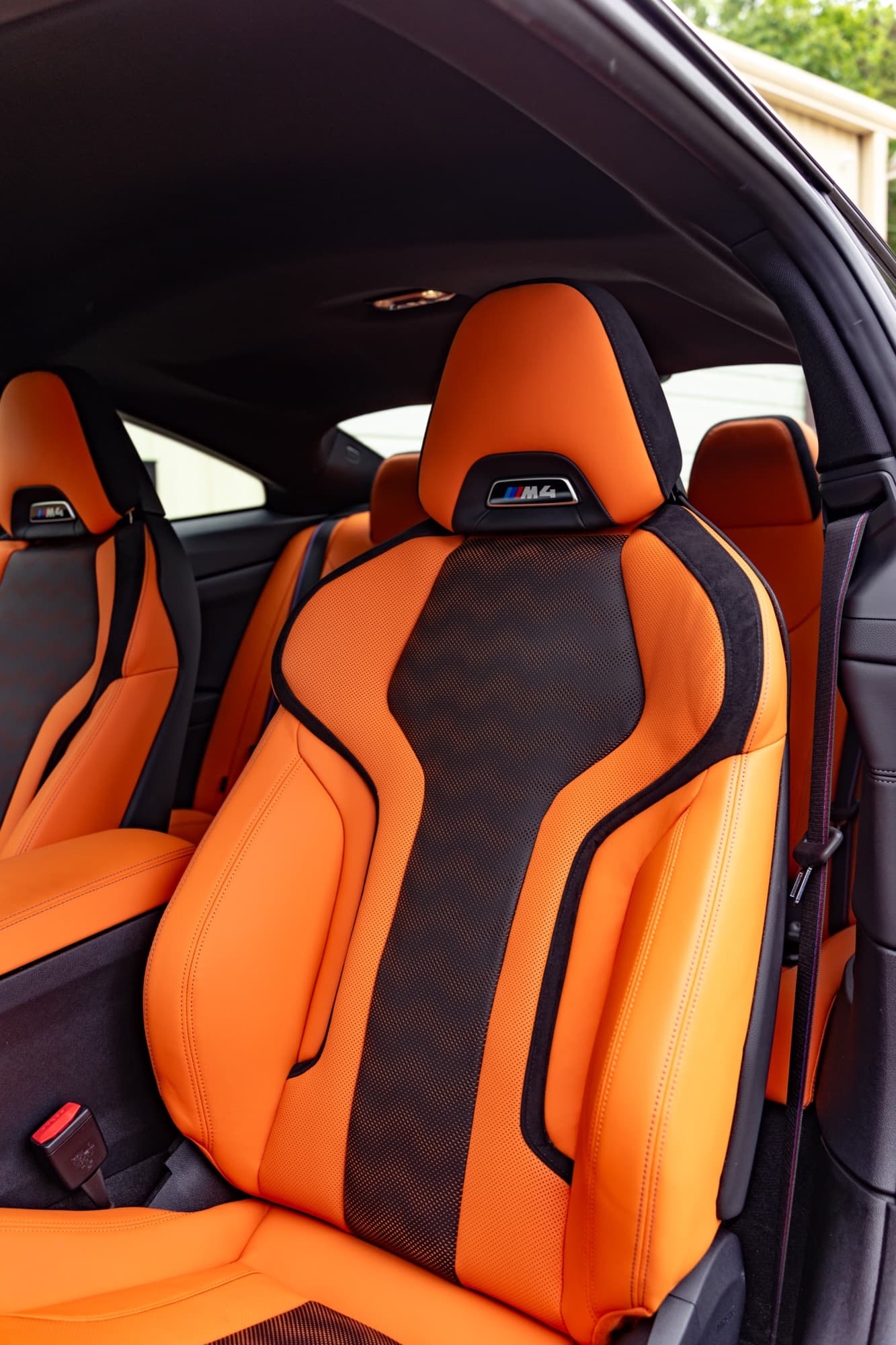 Orange and black leather sport seats inside a coupe with the door open