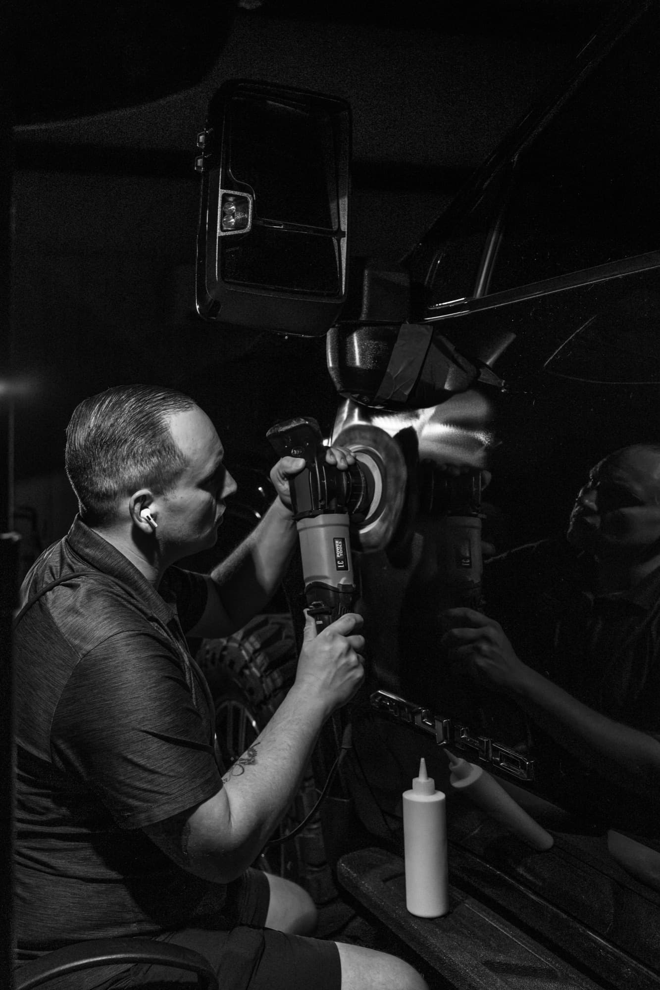Black and white photo of a detailer working with a rotary polisher