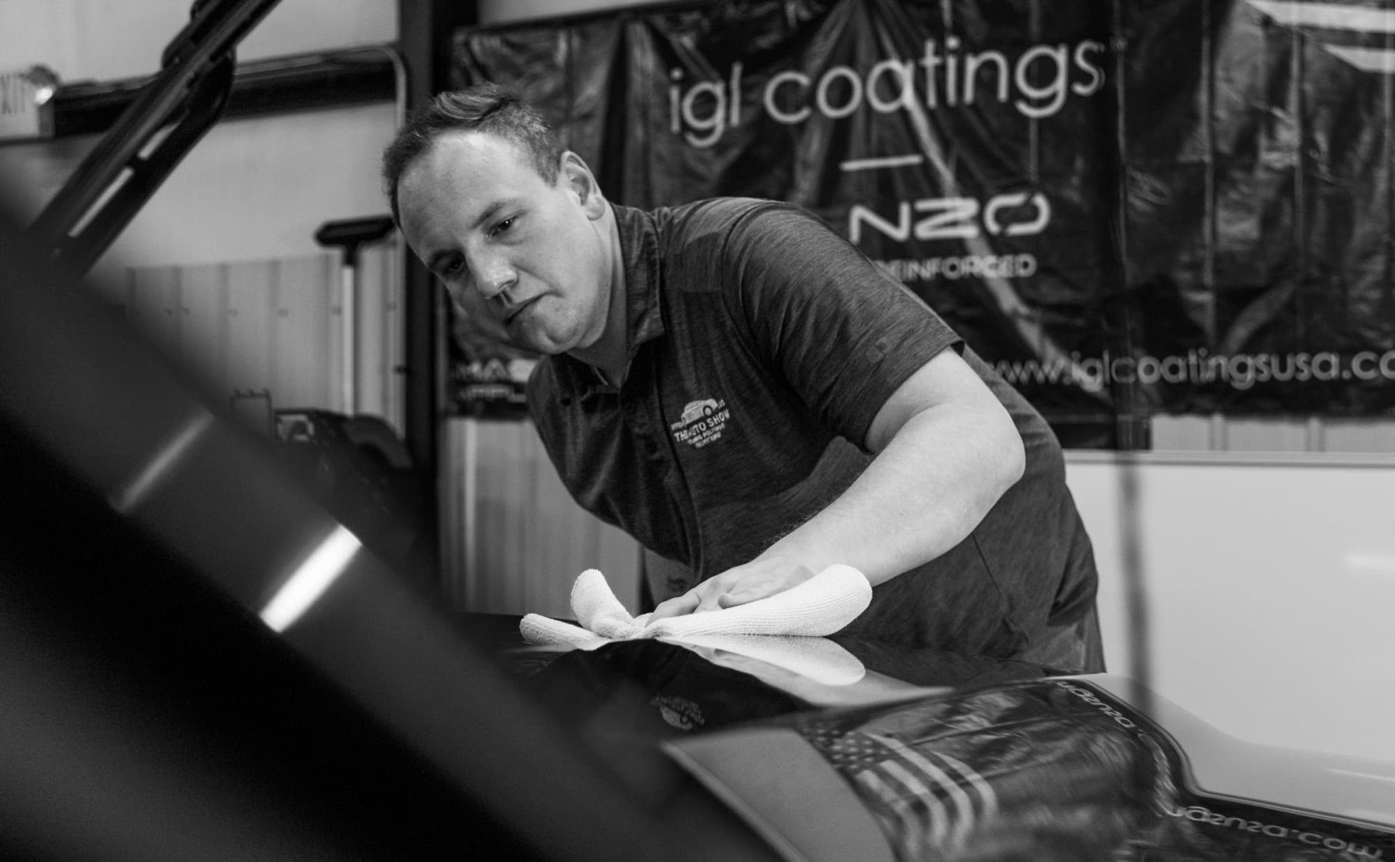 Black and white photo of a detailer wiping down a freshly polished hood