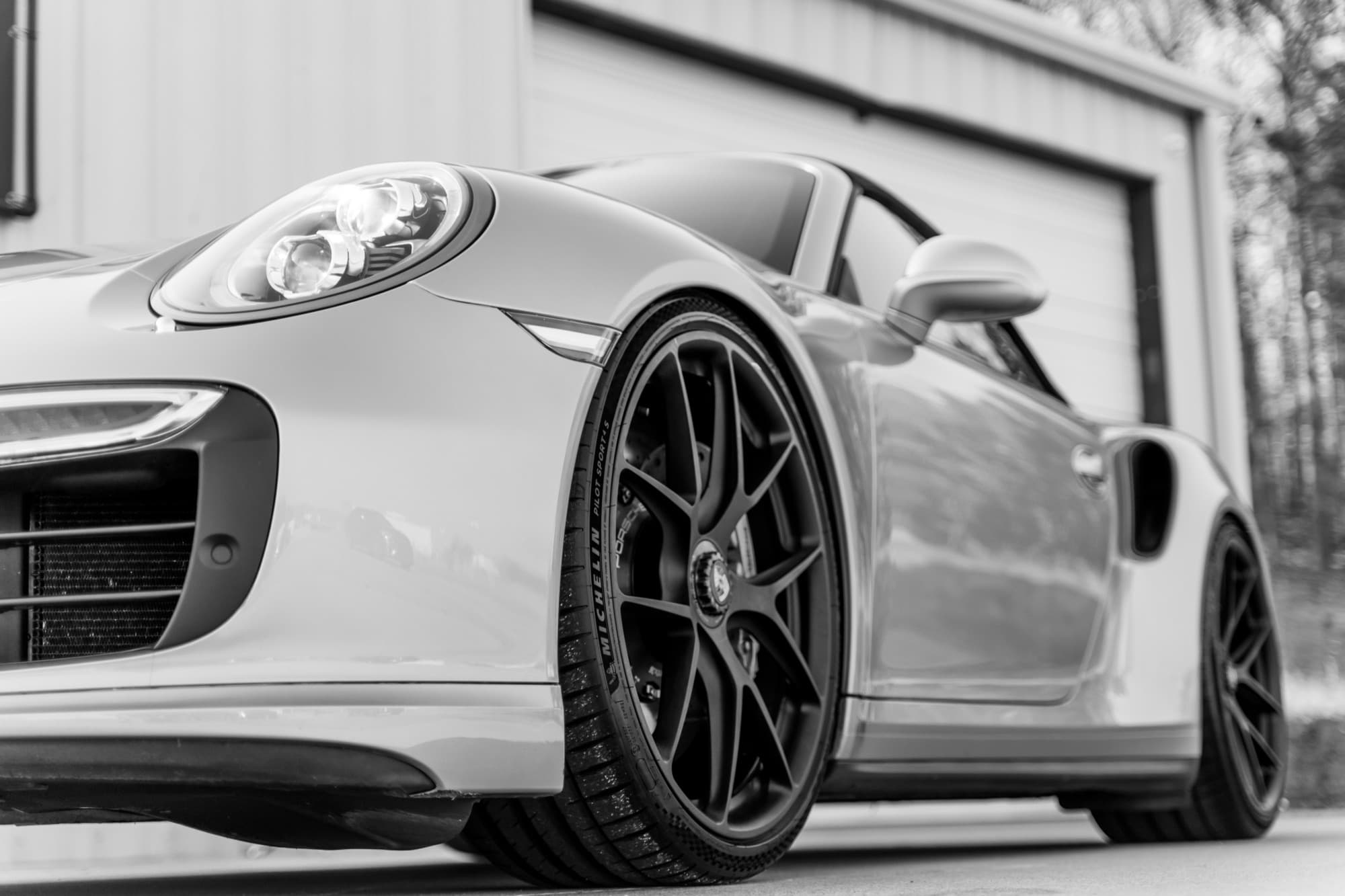 Black-and-white photo of the front of a Porsche 911 Turbo S with dark wheels