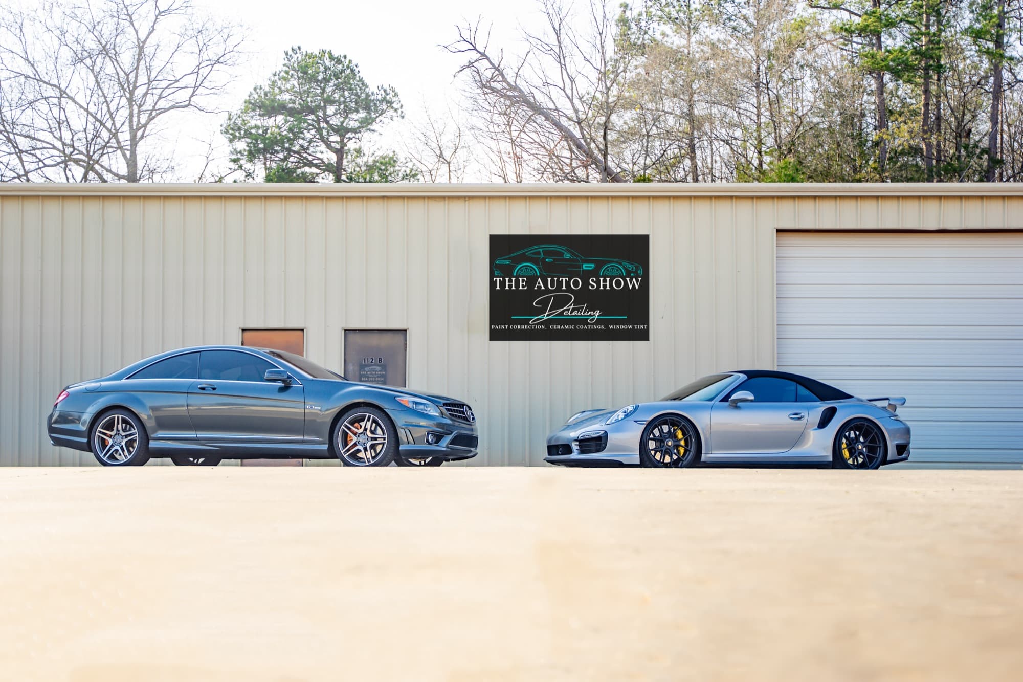 Two customer cars parked outside The Auto Show shop building