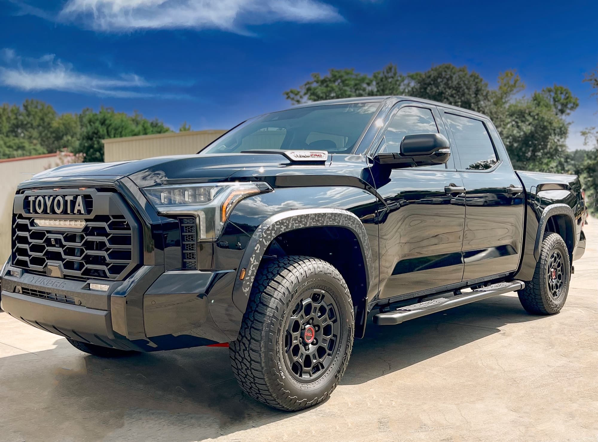 A black Toyota Tundra pickup parked on concrete under a blue sky
