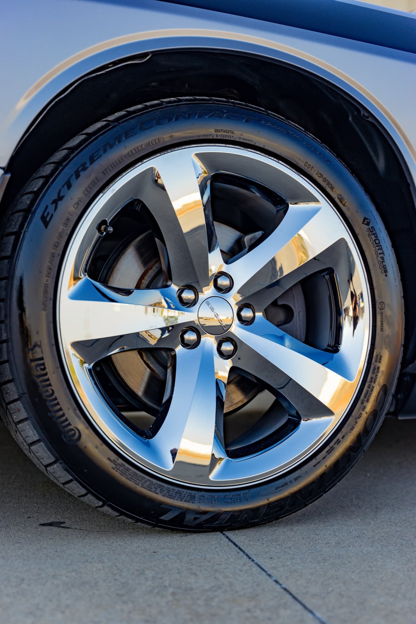 A clean chrome five-spoke wheel and tire on a silver car