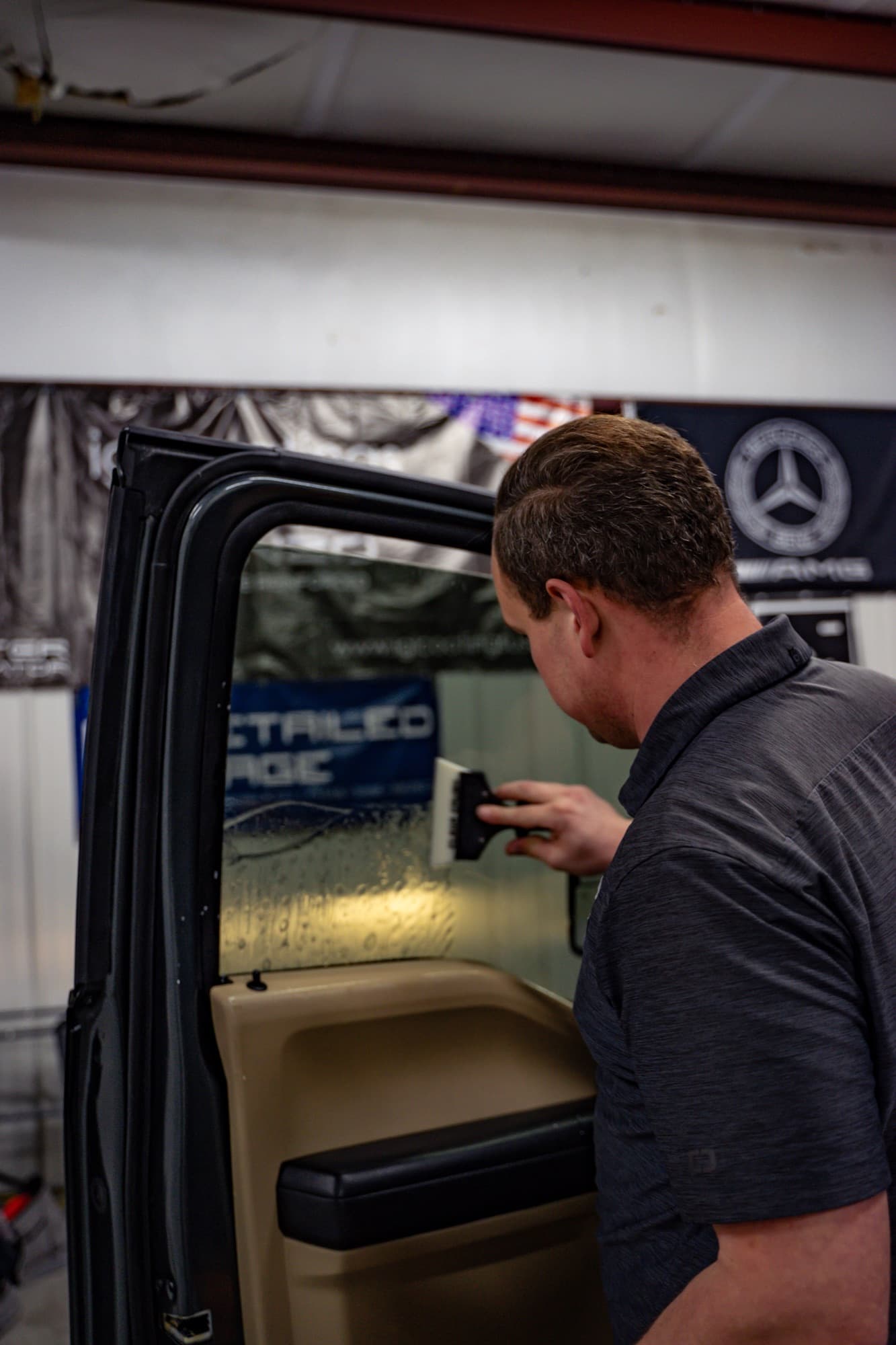 A technician working on the door glass of a pickup truck inside the shop